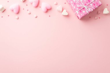 Sevgililer Günü konsepti. Paket kağıdındaki mevcut kutunun en üstteki fotoğrafında kalp desenli lokum mumları ve kopyalanmış açık pembe arkaplan üzerine serpiştirilmiş şekerlemeler var.