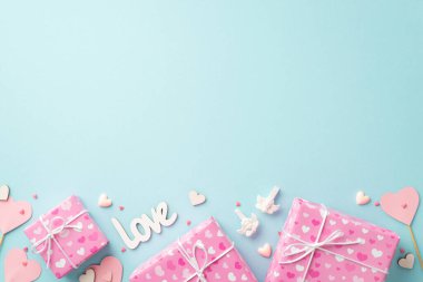 Sevgililer Günü konsepti. En üstteki fotoğraf pembe hediye kutularının kağıt kalpler çubukların üzerine kazınmış aşk tanrısı ve izole edilmiş pastel mavi arkaplan üzerine boşluklar serpiştirilmiş aşk tanrıçası.