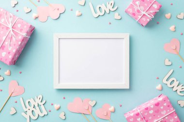Sevgililer Günü konsepti. Fotoğraf çerçevesinin en üstteki fotoğrafı pembe hediye kutuları çubukların üzerindeki kağıt kalpler yazıtlar sevgi ve izole edilmiş pastel mavi arka plan üzerinde kopyalanmış mavi arkaplan serpiştirmeler