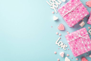 Sevgililer Günü konsepti. Pembe hediye kutularının en üstteki fotoğrafı kalp şeklinde marshmallow yazıtları izole edilmiş pastel mavi arka planda mumları ve serpintileri sever.