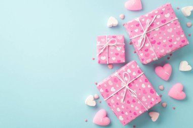 Sevgililer Günü konsepti. Üst görüntü pembe kutular kalp şekilli lokum mumlar ve kopyalanmış açık mavi arkaplan üzerine serpiştirilmiş şekerlemeler