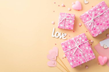 Sevgililer Günü konsepti. En üstteki resim pembe hediye kutuları yazıtlar aşk kağıt kalpler çubuklar üzerinde mum ve izole edilmiş bej arkaplan üzerinde serpiştirmeler