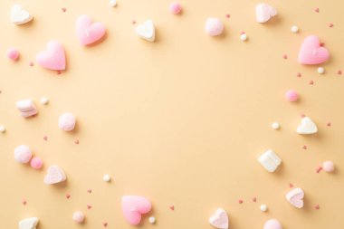 Sevgililer Günü konsepti. Kalp şeklindeki lokum şeklindeki pembe mumların en üstteki fotoğrafı izole edilmiş bej arkaplanda yumuşak ponpon ve serpiştirilmiş şekerlemeler ortada kopyalanmış boşluklar.