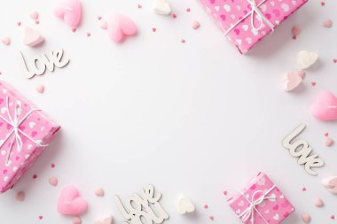 Sevgililer Günü konsepti. Üst görünüm pembe kutular kalp şekilli lokum mumlar yazılar izole edilmiş beyaz arkaplan üzerine sevgi ve serpiştirmeler ortada boş boşluk