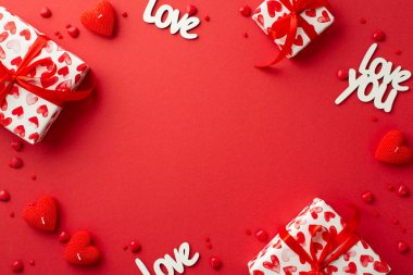 Sevgililer Günü konsepti. Hediye kutularının en üstteki fotoğrafı kalp şeklinde mumlar yazılar izole edilmiş kırmızı arkaplanda sevgi ve serpiştirmeler ortada kopyalanmış boşluk