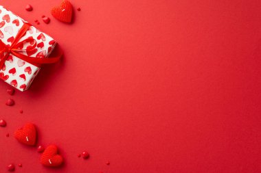 Sevgililer Günü konsepti. Mevcut kutucuk kalbin üst görünümü mum ve serpintiler izole edilmiş kırmızı arkaplan üzerinde kopyalanmış
