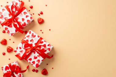 Sevgililer Günü konsepti. Mevcut kutuların, kurdele yay, kalp şekilli şekerler ve izole edilmiş açık bej arkaplan ve boş alan üzerine serpiştirilmiş şekerler.