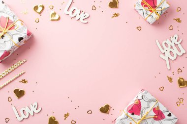 Sevgililer Günü konsepti. Hediye kutularının en üstteki fotoğrafı yazıtlar aşk pipetleri altın kalp şekilli konfeti ve izole edilmiş açık pembe arka plandaki pullar ortada kopyalanmış boşluk