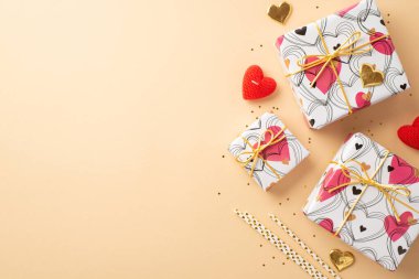 Sevgililer Günü konsepti. Şık hediye kutularının en üst görüntüsü kalp şeklinde mum altın konfeti ve izole edilmiş pastel bej arka planda boş alan ile pullar.