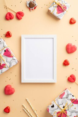 Sevgililer Günü konsepti. Fotoğraf çerçevesi hediye kutularının dikey resmi kalp şekilli lolipoplar çikolata kamışları ve izole edilmiş pastel bej arka planda altın pullar boş alan