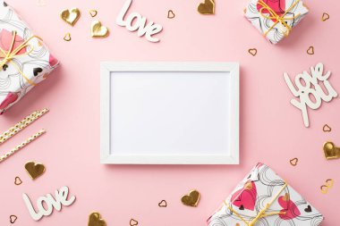 Sevgililer Günü konsepti. Fotoğraf çerçevesi hediye kutularının üst görüntüsü altın kalp şekilli konfeti yazıtları sizi seviyor ve boş arkaplan ile izole edilmiş pembe pastel arka planda pipetler.