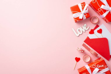 Sevgililer Günü konsepti. Üst görünüm kırmızı kutular içinde kurdele yay zarf içinde harf kalpler yazılı dekoratif bant ve kopyalanmış pastel pembe arka plan klipleri