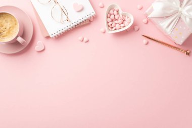 Valentine's Day concept. Top view photo of notebook stylish glasses pen heart shaped saucer with sprinkles present box and cup of coffee on isolated pastel pink background with empty space