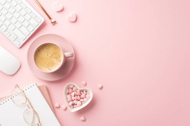 Valentine's Day concept. Top view photo of copybook keyboard computer mouse glasses pen heart shaped saucer with sprinkles and cup of coffee on saucer on isolated pastel pink background with copyspace