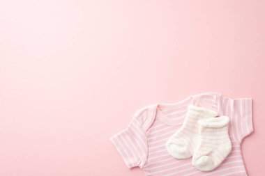 Infant clothes concept. Top view photo of pink shirt and tiny socks on isolated pastel pink background with copyspace