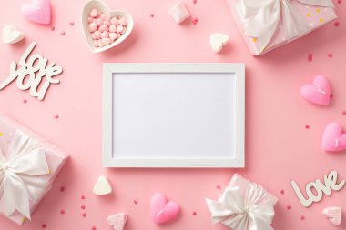 Valentine's Day concept. Top view photo of white photo frame gift boxes heart shaped saucer with sprinkles candles marshmallow and inscriptions love on isolated pastel pink background with blank space