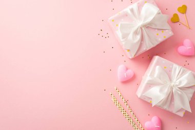 Valentine's Day decor concept. Top view photo of gift boxes with white ribbon bows golden hearts straws candles and shiny sequins on isolated light pink background with copyspace