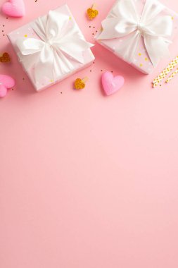 Valentine's Day concept. Top view vertical photo of present boxes with ribbon bows decorative clips heart shaped candles straws and golden sequins on isolated pastel pink background with empty space