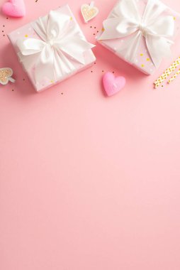 St Valentine's Day concept. Top view vertical photo of gift boxes with ribbon bows decorative clips heart shaped candles straws and golden sequins on isolated light pink background with empty space