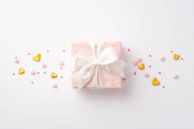 St Valentine's Day concept. Top view photo of big pastel pink present box with silk ribbon bow golden hearts and sprinkles on isolated white background