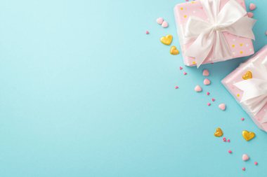 Valentine's Day concept. Top view photo of pastel pink present boxes with silk ribbon bows golden heart shaped confetti and sprinkles on isolated light blue background with copyspace