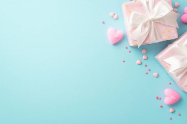 Valentine's Day concept. Top view photo of light pink present boxes with white ribbon bows heart shaped candles and sprinkles on isolated pastel blue background with copyspace
