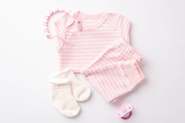 Baby clothes concept. Top view photo of pink shirt pants socks dummy and teether chain on isolated white background