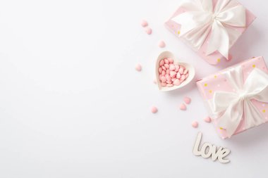 Valentine's Day concept. Top view photo of pastel pink gift boxes with white ribbon bows heart shaped plate with sprinkles and inscription love on isolated white background with copyspace