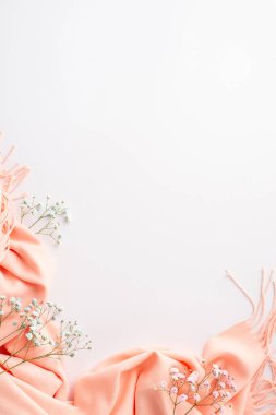 Hello spring concept. Top vertical view photo of pink soft scarf and gypsophila flowers on isolated white background with blank space