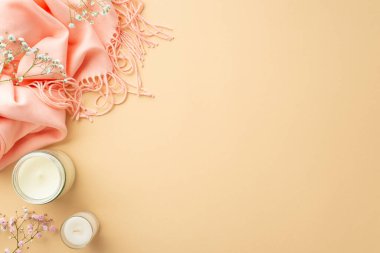 Spring aesthetic concept. Top view photo of candles in glass pink soft plaid and gypsophila flowers on isolated pastel beige background with empty space