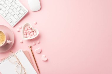 Valentine's Day concept. Top view photo of notepad pen keyboard computer mouse glasses heart shaped plate with sprinkles and cup of coffee on saucer on isolated pastel pink background with empty space