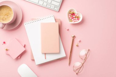Valentine's Day concept. Top view photo of reminders golden pen glasses heart shaped saucer pushpins sticky note paper keyboard computer mouse and mug of coffee on isolated pastel pink background
