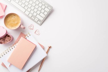 Valentine's Day concept. Top view photo of keyboard pink notepads golden pen heart shaped clips holder and cup of frothy drinking on isolated white background with copyspace