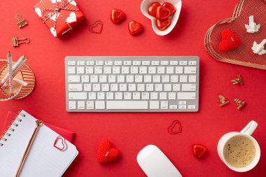 8-march concept. Top view photo of keyboard computer mouse notepads pen heart shaped saucer with candies golden binder clips stationery holders giftbox candles mug of coffee on isolated red background