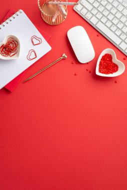 Valentine's Day concept. Top view vertical photo of diaries heart shaped saucer with sprinkles keyboard computer mouse pencils holder clips and golden pen on isolated red background with empty space