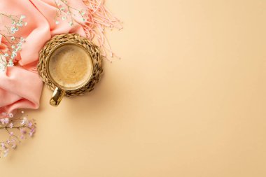 Hello spring concept. Top view photo of cup of fresh coffee on rattan serving mat pink soft plaid and gypsophila flowers on isolated pastel beige background with blank space