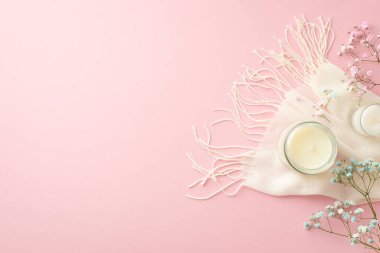 Hello spring concept. Top view photo of candles in glasses gypsophila flowers and white scarf on isolated light pink background with empty space