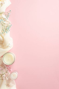 Hello spring concept. Top view vertical photo of candles in glasses pink and blue gypsophila flowers and white cozy plaid on isolated light pink background with blank space