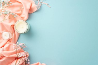Hello spring concept. Top view photo of candles in glass holders gypsophila flowers and pink plaid on isolated pastel blue background with copyspace