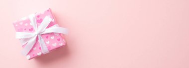 Gender reveal party concept. Top view photo of pink giftbox with white ribbon bow on isolated pastel pink background with copyspace