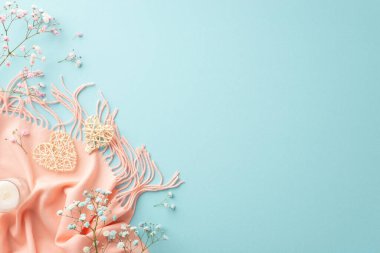 Hello spring concept. Top view photo of two rattan hearts small candle in glass gypsophila flowers and pink scarf on isolated light blue background with copyspace
