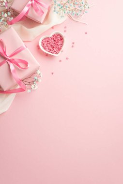 Spring concept. Top view vertical photo of pink gift boxes with bows white scarf heart shaped saucer with sprinkles and gypsophila flowers on isolated pastel pink background with copyspace