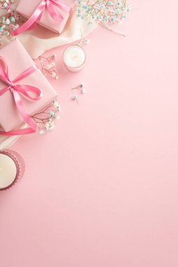Spring concept. Top view vertical photo of pink present boxes with ribbon bows white soft plaid candles and gypsophila flowers on isolated pastel pink background with empty space