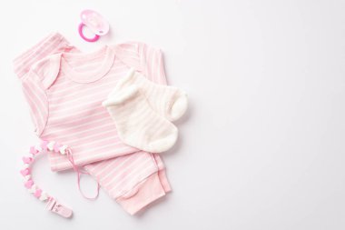 Baby shower concept. Top view photo of pink shirt pants socks pacifier and teether chain on isolated white background with copyspace