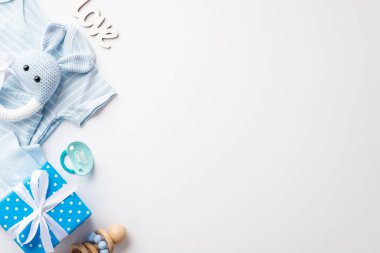 Baby shower concept. Top view photo of blue infant clothes giftbox knitted bunny rattle toy pacifier and inscription love on isolated white background with copyspace