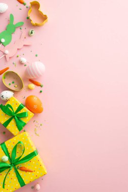 Easter concept. Top view vertical photo of colorful easter eggs yellow gift boxes with bows bunny silhouettes small carrots baking molds and sprinkles on isolated pastel pink background with copyspace