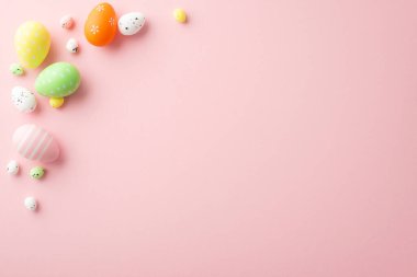 Easter concept. Top view photo of orange green yellow easter eggs on isolated light pink background with empty space
