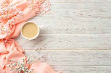 Hello spring concept. Top view photo of mug of coffee gypsophila flowers and pink plaid on grey wooden desk background with empty space