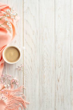 Hello spring concept. Top view vertical photo of cup of fresh coffee gypsophila flowers and pink soft plaid on grey wooden table background with copyspace