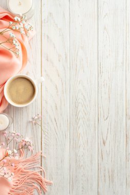 Hello spring concept. Top view vertical photo of mug of cocoa candles gypsophila flowers and pink soft plaid on grey wooden table background with copyspace
